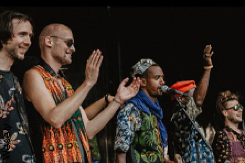 Eine Musikgruppe steht auf einer Bühne und performt.