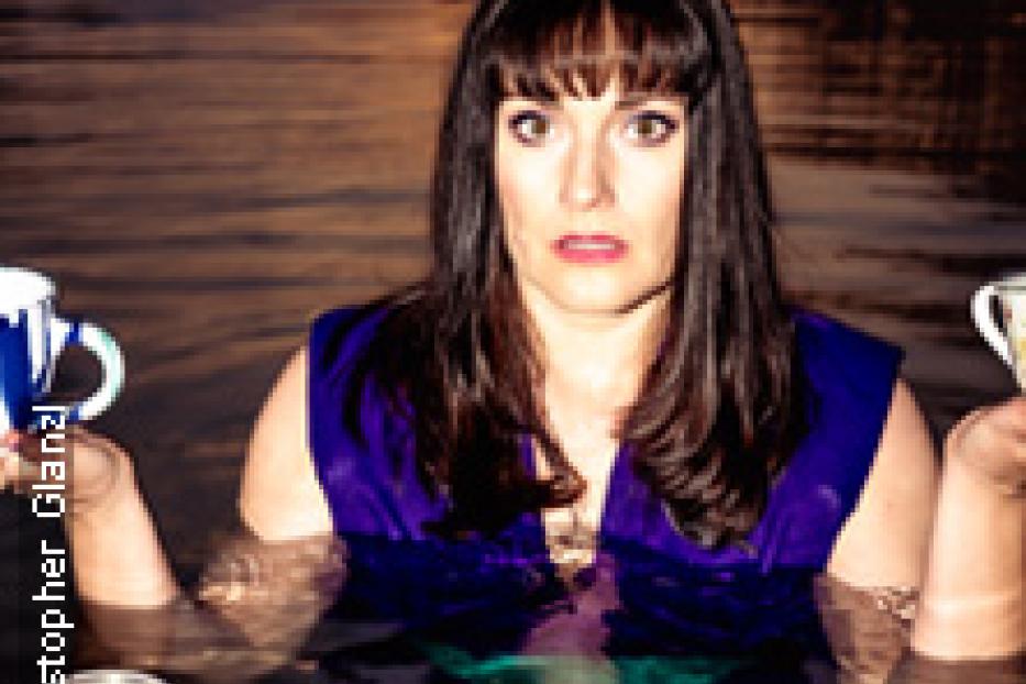 Eine Frau steht bis zur Brust im Wasser und hält Tassen in den Händen.