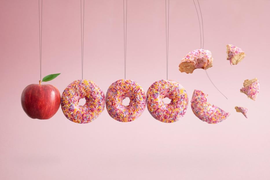 Donuts an einer Schnurr herabhängend und ein Apfel