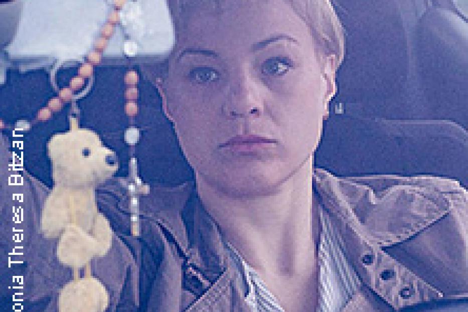 Eine Frau mit kurzem blonden Haar sitzt in einem Auto.