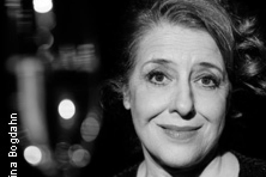 Schwarzweiß-Porträt einer lächelnden Frau mit lockigem Haar.