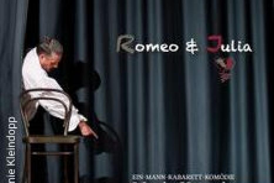 Ein Mann sitzt auf einem Stuhl vor einem Vorhang mit dem Titel „Romeo & Julia“.