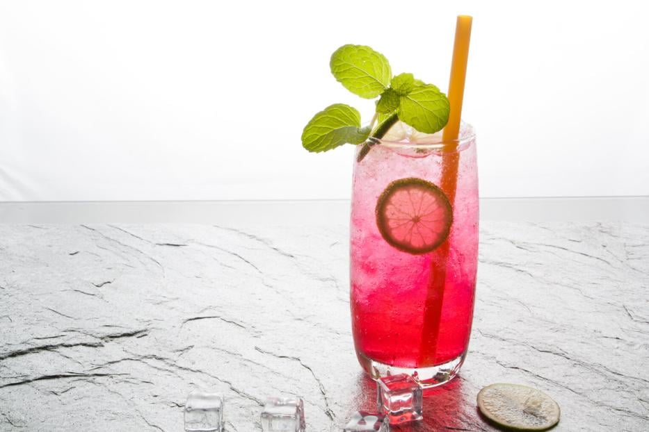 red soda lime drink with lime on stone.
