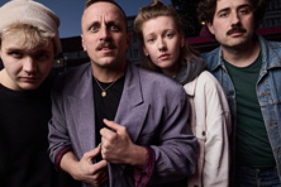 Eine Gruppe von vier jungen Erwachsenen posiert für ein Foto im Freien.