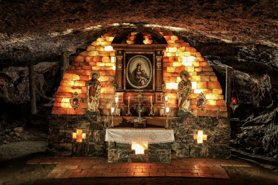 Eine Kapelle in einer Höhle, geschmückt mit Heiligenstatuen und einem Marienbild.