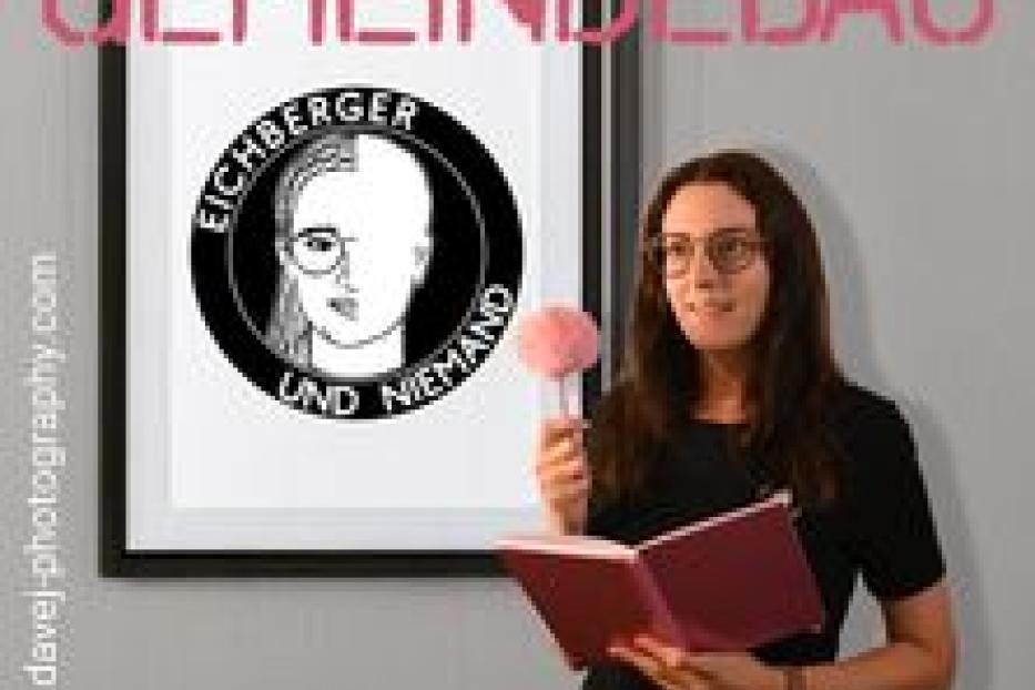 Eine Frau steht vor einem Bild mit der Aufschrift „Gemeindebau“ und dem Porträt einer Person.