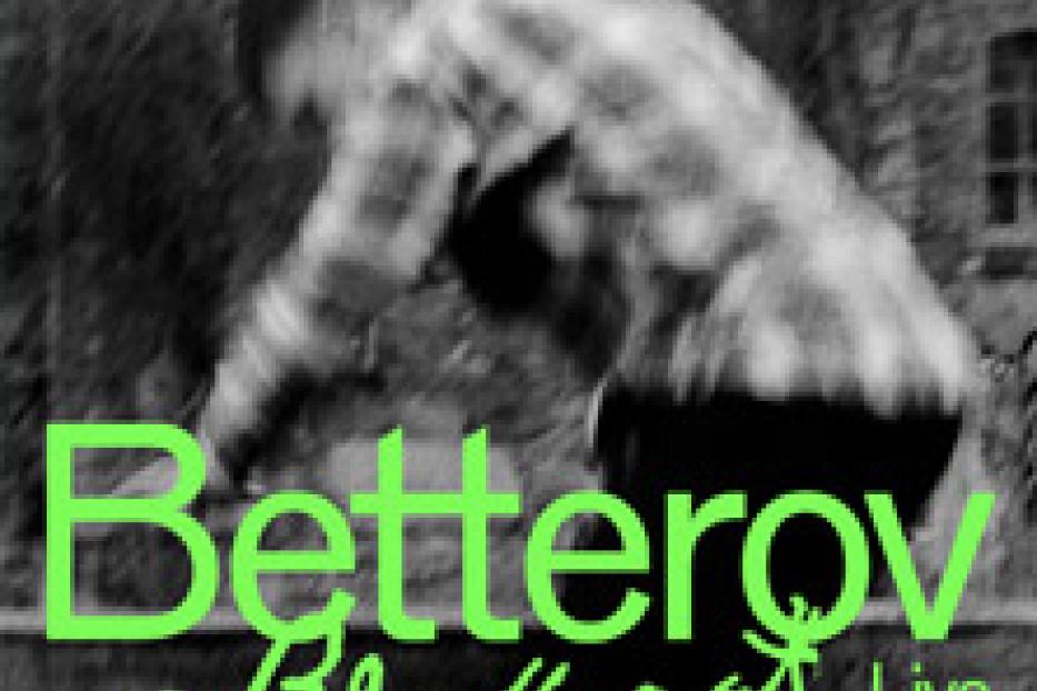 Ein Mann in einem karierten Hemd beugt sich vor, im Hintergrund ein Gebäude. Der Schriftzug „Betterov große Kunst Live“ ist zu sehen.