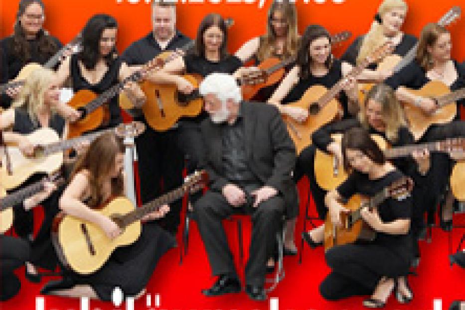 Eine Gruppe von Gitarristen spielt gemeinsam auf der Bühne bei einem Jubiläumskonzert.