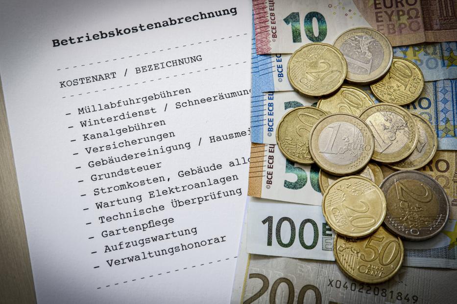 Eine Betriebskostenabrechnung liegt neben Euro-Banknoten und Münzen.