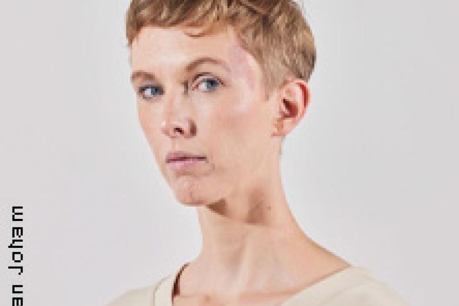 Porträt einer jungen Frau mit kurzen blonden Haaren und hellblauer Kleidung.