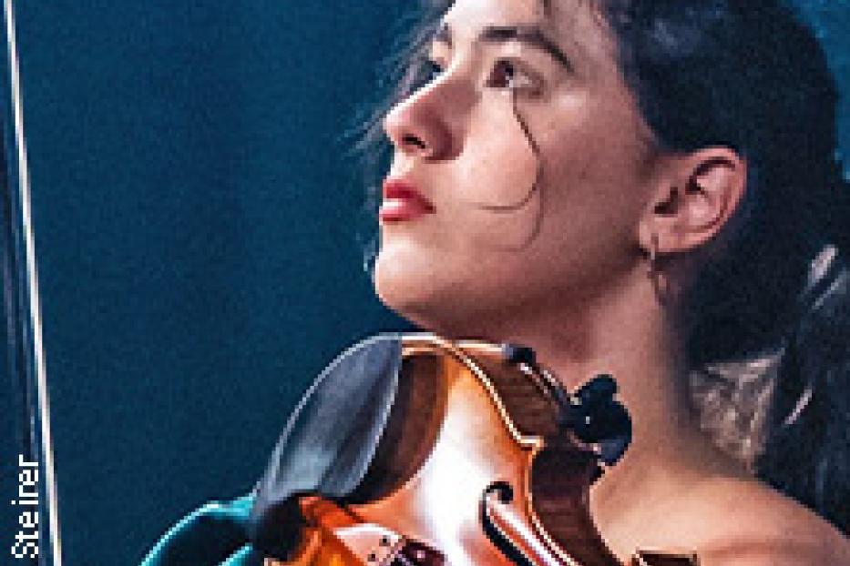 Eine junge Frau spielt Violine, den Kopf leicht zur Seite geneigt.