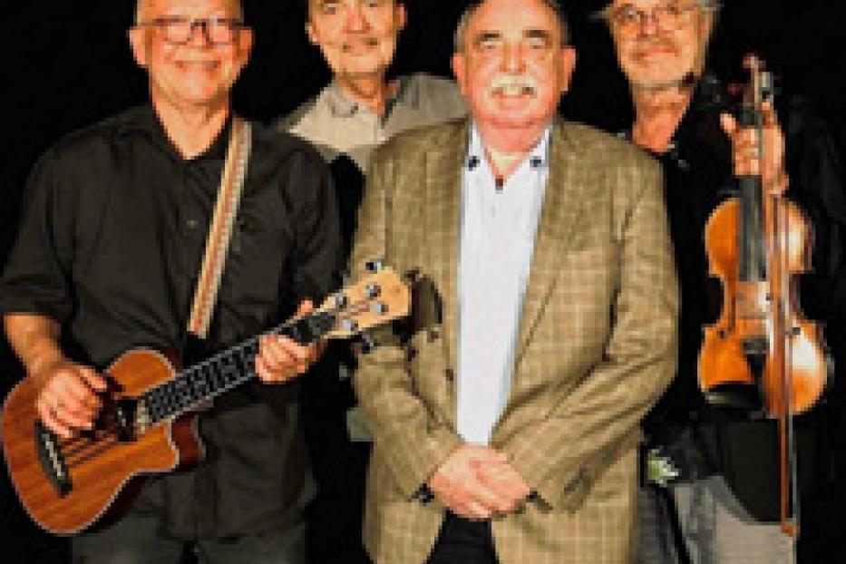Eine Band mit vier Mitgliedern posiert mit ihren Instrumenten vor einem schwarzen Hintergrund.