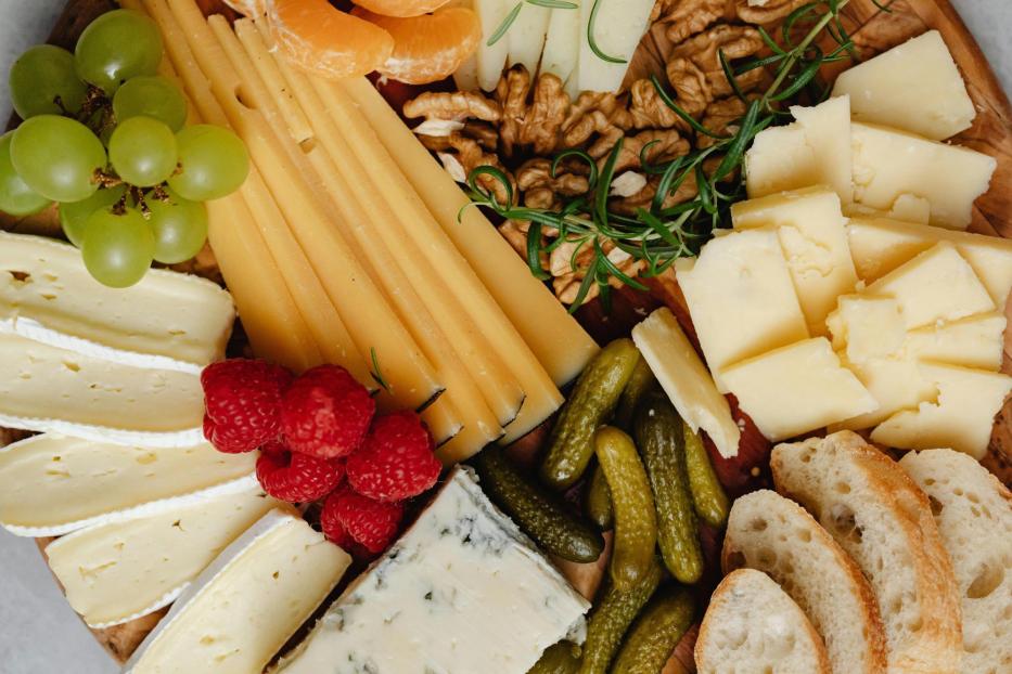 Eine Platte mit verschiedenen Käsesorten, Gemüse, Obst und Brot.