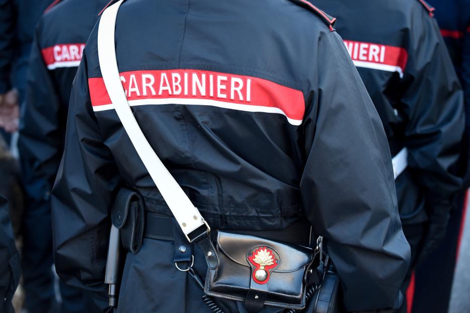Ein Carabinieri-Beamter in Uniform mit Schulterriemen und Tasche ist von hinten zu sehen.
