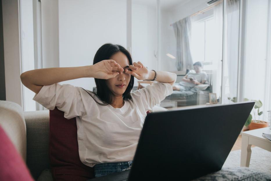 Erschöpfte Frau im HomeOffice am Laptop