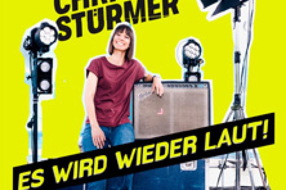 Christina Stürmer lehnt an einem Verstärker, umgeben von Scheinwerfern, mit dem Albumtitel „Es wird wieder laut!“.