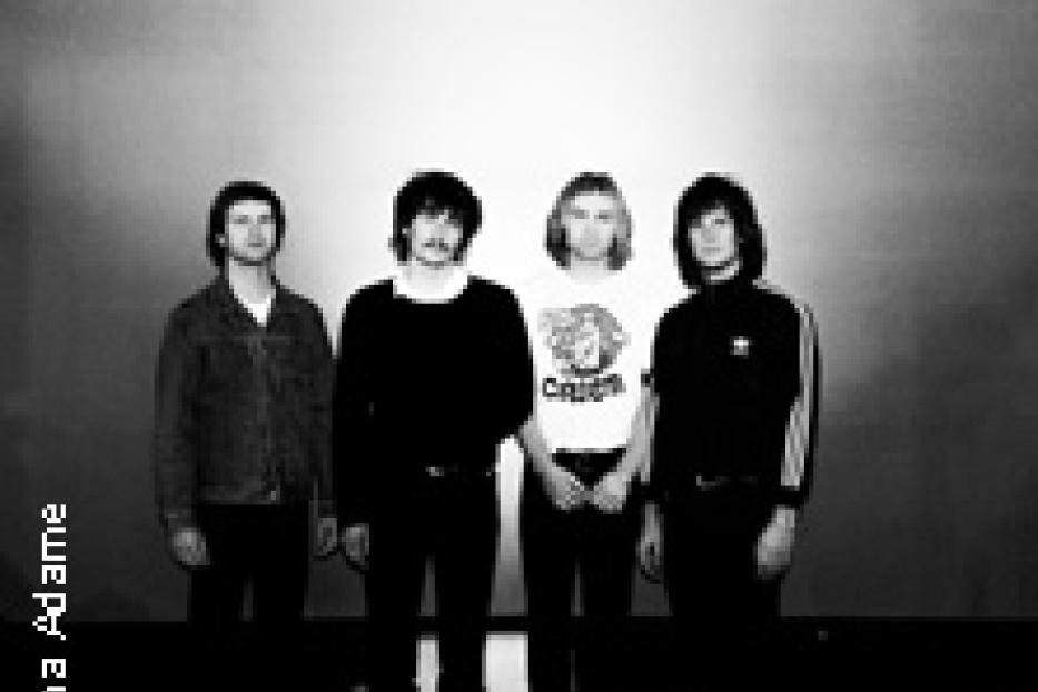 Die Band The Motors posiert vor einer Wand.