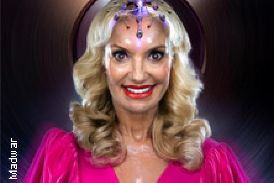 Eine Frau mit blonden Locken und einem pinkfarbenen Kleid lächelt in die Kamera.