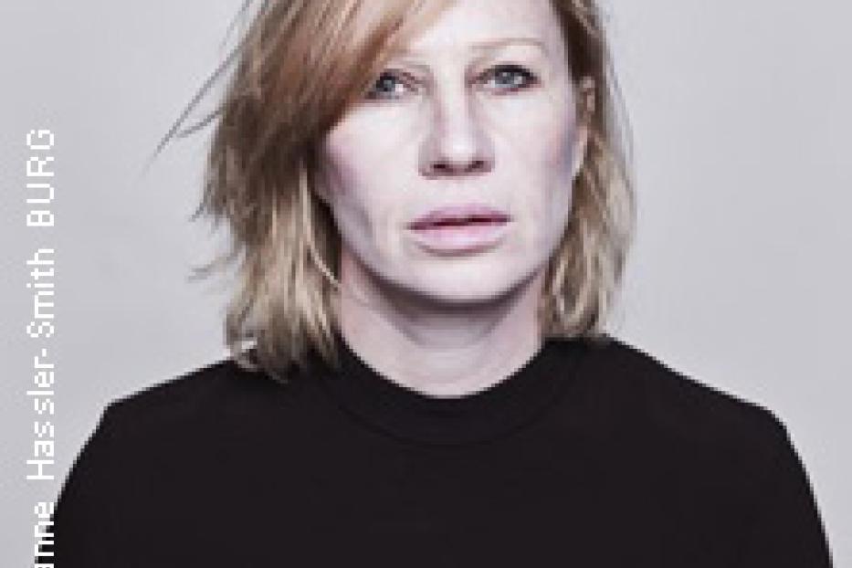 Porträt einer Frau mit blonden, schulterlangen Haaren und einem schwarzen Oberteil.