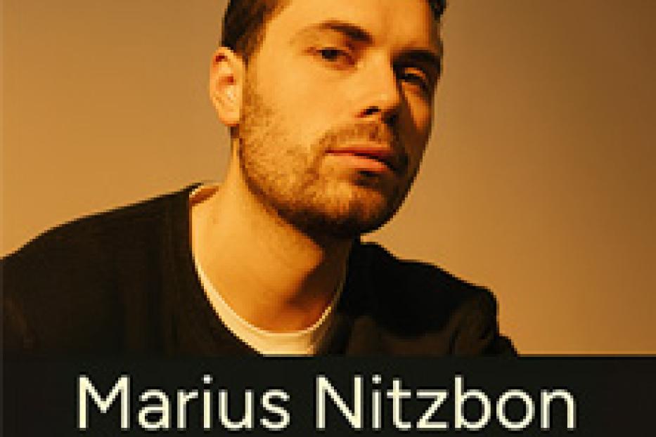 Ein Porträt des Musikers Marius Nitzbon vor einem beigen Hintergrund.