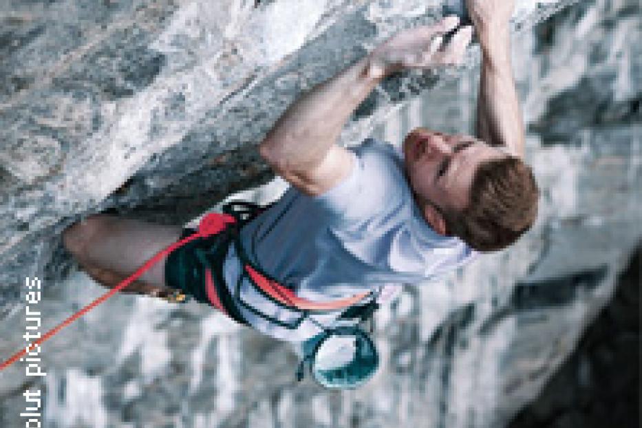 Ein Mann klettert an einer steilen Felswand.