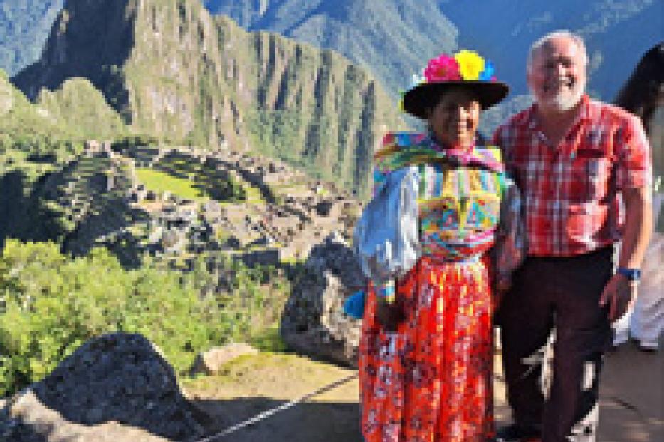 Ein Mann und eine Frau in traditioneller Kleidung posieren vor Machu Picchu.