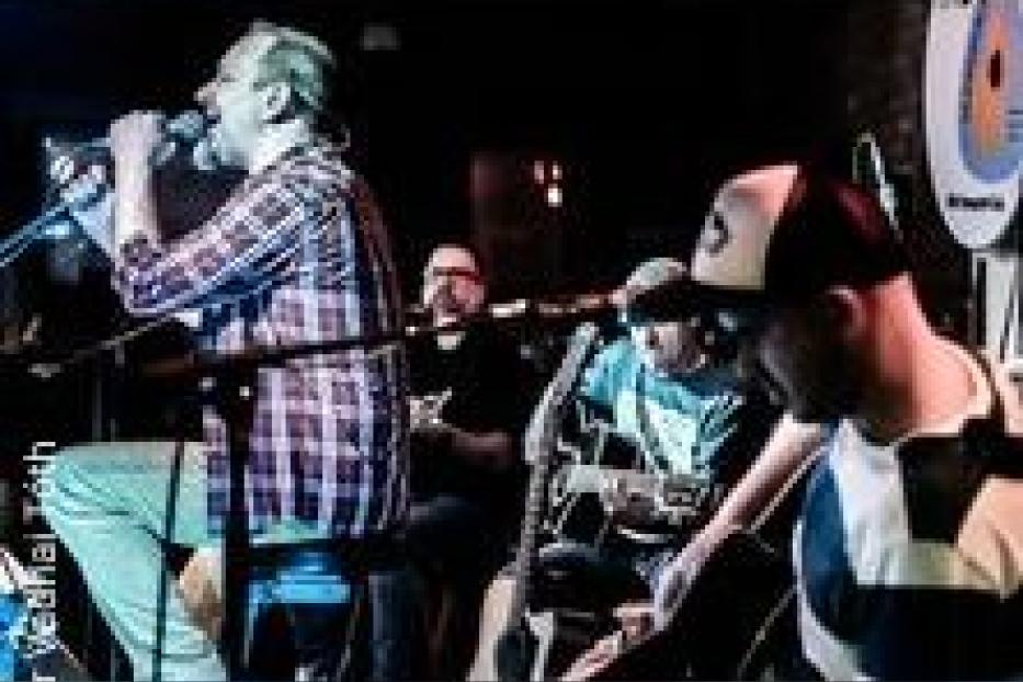 Eine Band tritt live auf der Bühne auf, der Sänger singt ins Mikrofon.