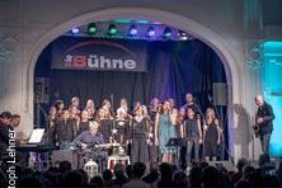 Ein Chor tritt auf einer Bühne vor Publikum auf.