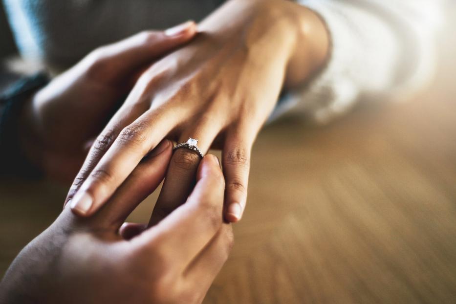 Mann steckt Ring an den Ringfinger einer Frau