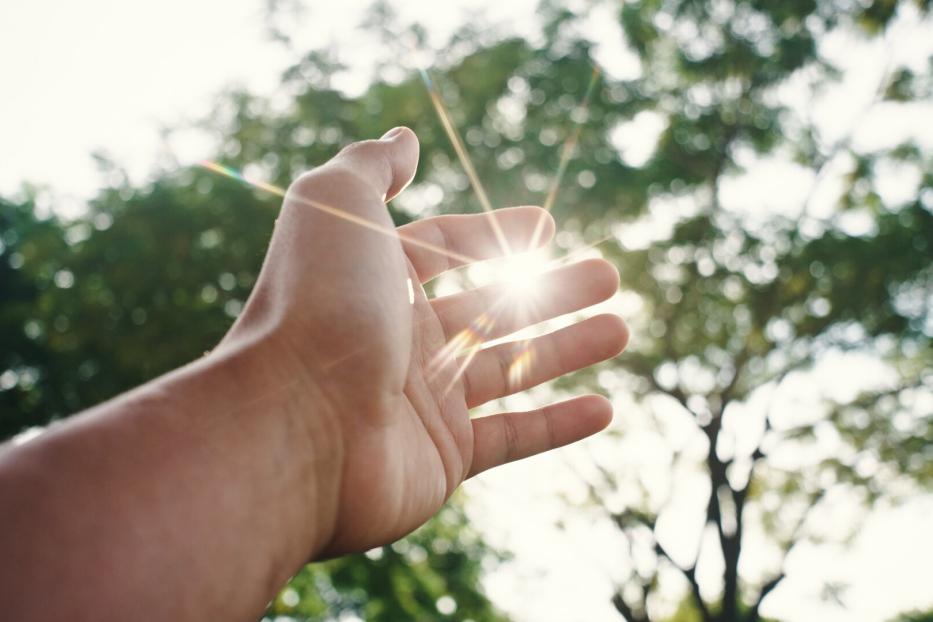 Ausgetreckte Hand, die nach der Sonne greift