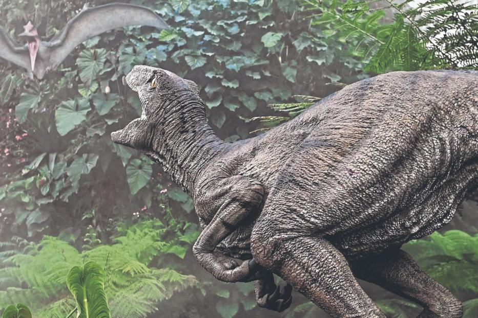 Ein Dinosaurier und ein Flugsaurier stehen inmitten dichter Vegetation, umgeben von Farnen und tropischen Pflanzen.