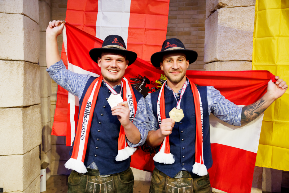 Zwei Männer halten die österreichische Flagge hoch. 