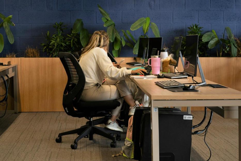 Frau sitzt auf schwarzem Bürostuhl am Arbeitsplatz