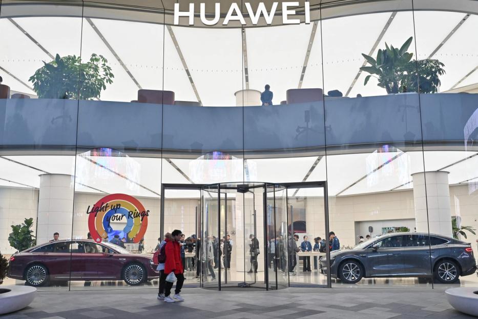 Großes, modernes Huawei-Geschäft mit Glasfassade, zwei ausgestellten Autos und mehreren Menschen im Inneren.