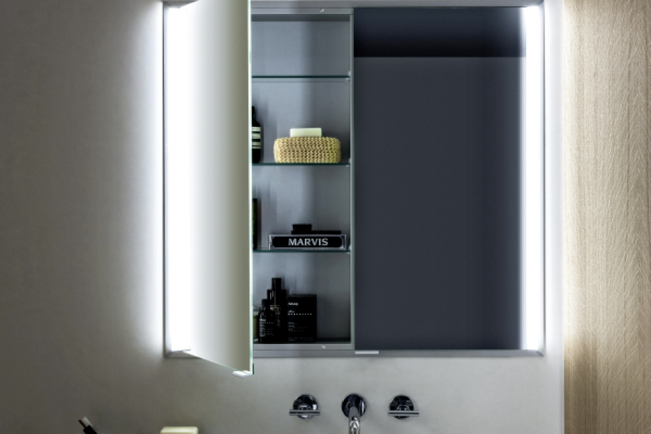 Moderner Badezimmerspiegel mit geöffneter beleuchteter Tür, weißes Waschbecken, Seifenspender und graue Wand.