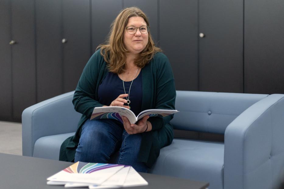 Margreth Keiler sitzt auf einer Couch mit aufgeschlagenem Bericht