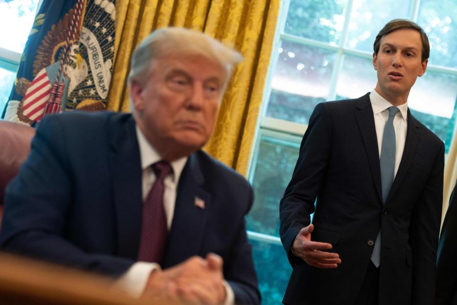 Donald Trump sitzt am Schreibtisch, während Jared Kushner im Anzug spricht.