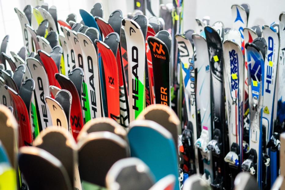 Viele gebrauchte Ski verschiedener Marken stehen dicht nebeneinander in einem Raum.