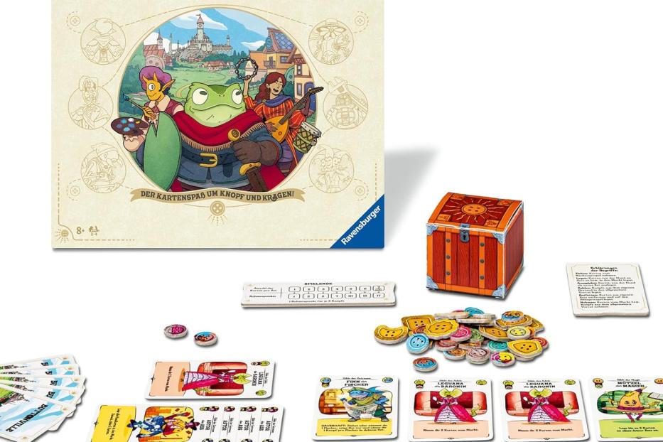 Spielschachtel von „Die glorreichen Gilden von Buttonville“ von Ravensburger mit Spielmaterial wie Karten, Chips und einer kleinen Schatztruhe auf einem Tisch.