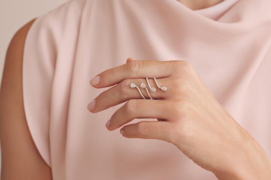 Eine Frau im rosa Kleid mit einem silbernen Ring am Finger, den sie in die Kamera hält