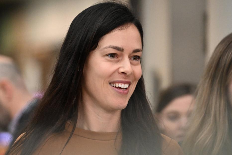 Eine lächelnde Ana Ivanovic mit langem, dunklem Haar trägt ein braunes Oberteil.