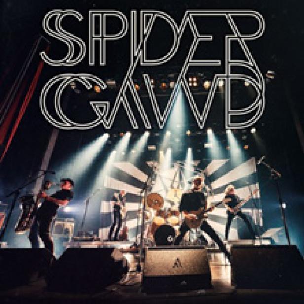 Die Band Spidergawd spielt live auf einer Bühne mit Scheinwerfern und einem schwarz-weiß gestreiften Hintergrund.