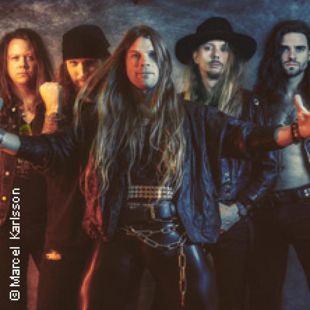 Eine Heavy-Metal-Band posiert in Lederkleidung für ein Gruppenfoto.
