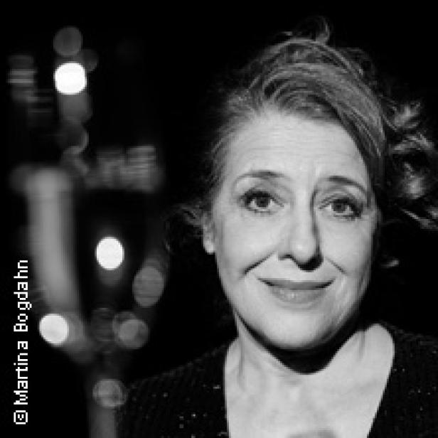 Schwarzweiß-Porträt einer lächelnden Frau mit lockigem Haar.