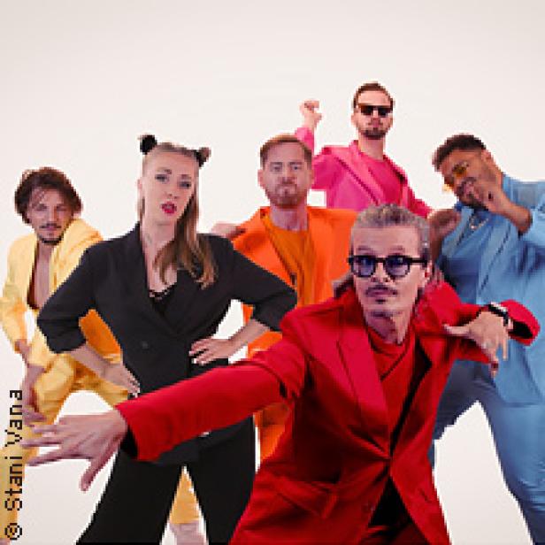 Die deutsche Band Marquess posiert in farbenfrohen Anzügen vor einem hellen Hintergrund.