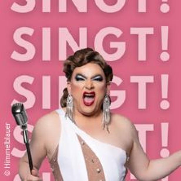 Eine Dragqueen mit Mikrofon singt vor einem pinkfarbenen Hintergrund mit dem Wort „Singt!“.