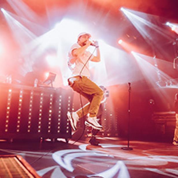 Ein Sänger springt mit einem Mikrofon in der Hand auf einer Bühne.