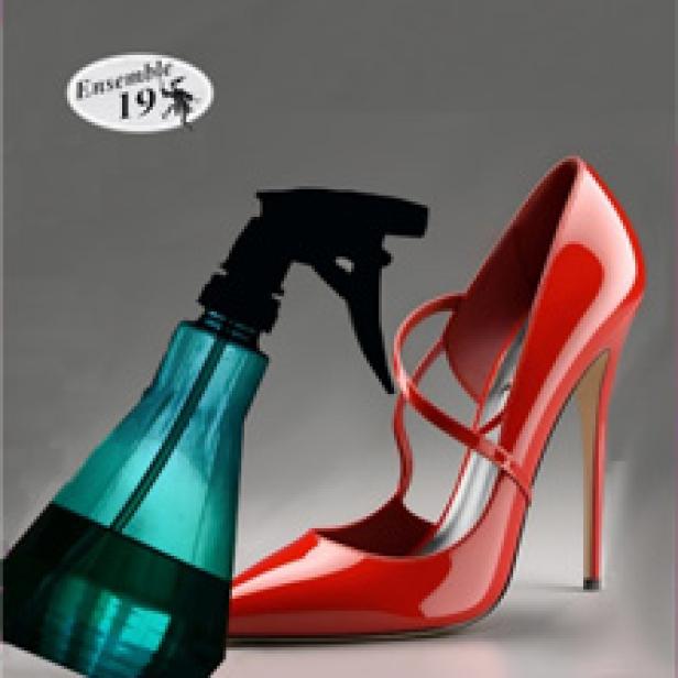 Ein roter High Heel steht neben einer blauen Sprühflasche.