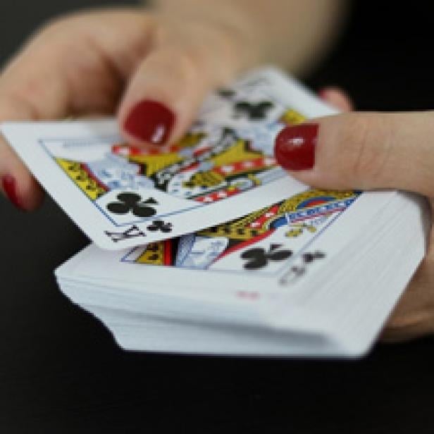 Eine Person mischt einen Stapel Spielkarten.