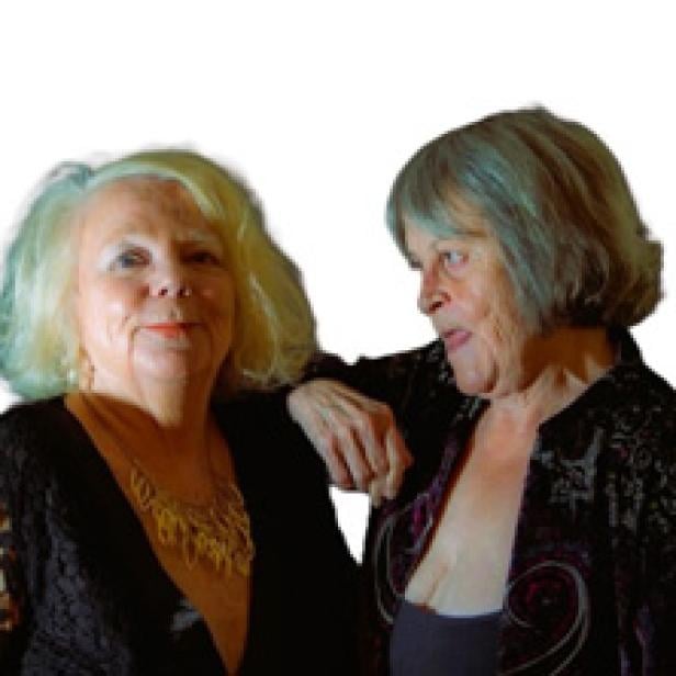 Zwei ältere Frauen stehen nebeneinander und lächeln.